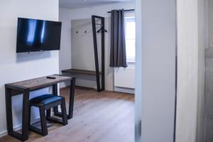 Kleines Zimmer mit einem Tisch und einem TV. in der Unterkunft Hotel Pame Grill in Eching