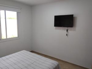 a white room with a bed and a flat screen tv at Casa Las Moras in San Rafael