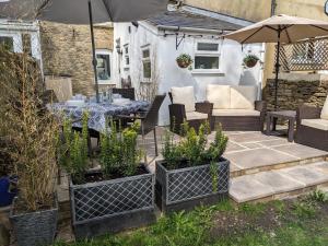 a patio with a table and chairs and an umbrella at The Cottage in Tetbury