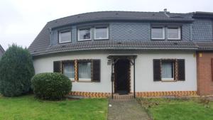 a white house with a black roof and a door at Cozy villa with garden, balcony and parking area in Düsseldorf in Düsseldorf