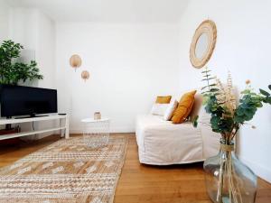 uma sala de estar com um sofá branco e uma televisão em Le Cosy Palm Tree by Madame Conciergerie em Bruz