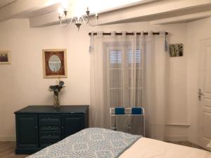 ein Schlafzimmer mit einem Bett, einer Kommode und einem Fenster in der Unterkunft Gîte des Lavandes in Oradour-Fanais