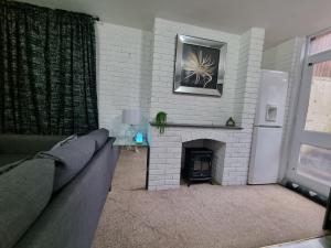 ein Wohnzimmer mit einem Sofa und einem Kamin in der Unterkunft Quantock Lodge Vicarage 1 in Rochester