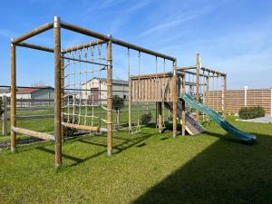 a playground with two swings and a slide at Huis Marlin in De Haan
