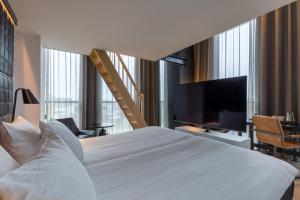 a bedroom with a large white bed and a television at Leonardo Hotel Groningen in Groningen