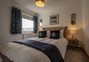 a bedroom with a bed with blue curtains and a window at Canalside Apartment in Fort William