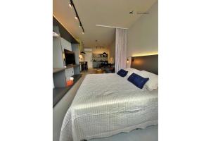 a bedroom with a large white bed with blue pillows at Home Time Studios in Florianópolis