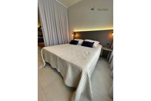 um quarto com uma cama com lençóis brancos e almofadas azuis em Home Time Studios em Florianópolis