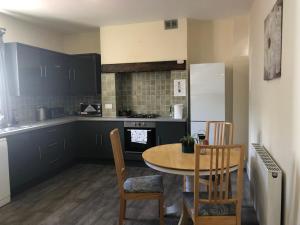 a kitchen with a table and chairs and a kitchen with black cabinets at Perfectly located in central Cheltenham for Cricket Festival from 8th to 24th Aug , Free Parking by reservation only Features en-suite or shared bathroom rooms Fully equipped kitchen and laundry facilities Ideal for longer stays in Cheltenham