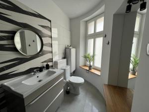 a bathroom with a sink and a toilet and a mirror at Melody Apartment in Krakow
