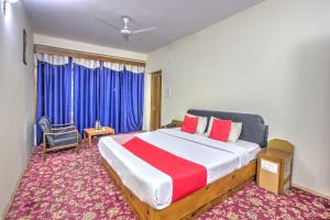 a bedroom with a large bed in a room with blue curtains at Hotel Shishamaati in Kulu