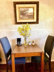 una mesa de madera con 2 sillas y un jarrón con flores. en Mountain Harbor Queen Guest Room on Lake Ouachita, en Mount Ida