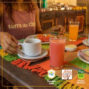 a woman sitting at a table with a cup of coffee at POUSADA VILA ACONCHEGO- Sossego- Em Meio Há Mata Nativa- by MARCOS MICOZZI in Serra do Cipo +56 photos