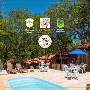 a swimming pool with chairs and a table and an umbrella at POUSADA VILA ACONCHEGO- Sossego- Em Meio Há Mata Nativa- by MARCOS MICOZZI in Serra do Cipo