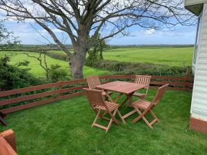 una mesa de madera y sillas sobre la hierba en Coed Bach, Nr Rhosneigr, Anglesey (Pet Friendly) en Rhosneigr