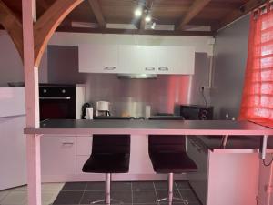 a kitchen with a pink counter with two stools at Residence Chez Marraine BERTILI in Le Gosier