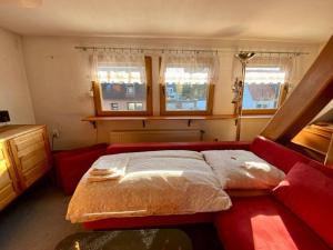 a bedroom with a red bed and two windows at Cozy villa with garden, balcony and parking area in Düsseldorf in Düsseldorf