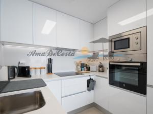 cocina con armarios blancos y microondas en CASCADA del MAR II - GRAN ALACANT, en Gran Alacant