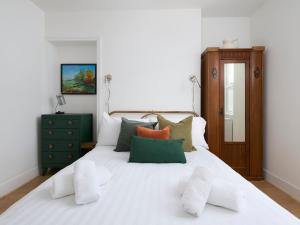 a white bed with green and orange pillows on it at Saltwater Cottage in Torquay