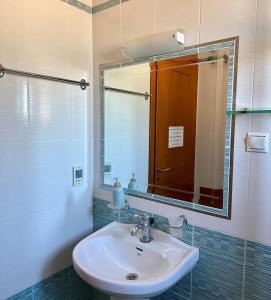 ein Bad mit einem Waschbecken und einem Spiegel in der Unterkunft Sofotel in Koroni
