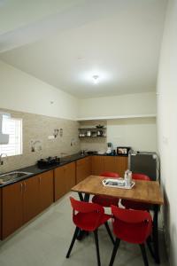 a kitchen with a wooden table and red chairs at Castle Suites by Haven Homes, Kempegowda International Airport road in Bangalore