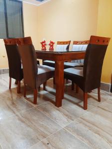 a wooden dining room table with two chairs and a table at Casa La Ruta Jardines in Pisco