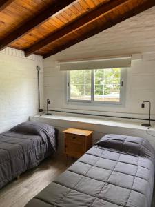 two beds in a room with a window at La Franca Cabaña de Veraneo in Villa General Belgrano