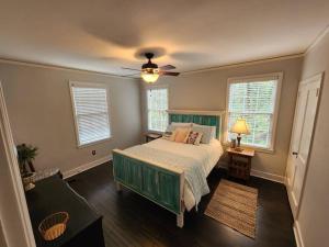 a bedroom with a green bed and two windows at Historic Ingleside Avenue Charm in Macon