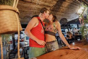 Ein Mann und eine Frau küssen sich an einem Tisch in der Unterkunft LEO HOSTEL in Baan Tai