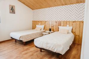 2 letti in una camera con pareti in legno e pavimenti in parquet di Forno House - O Lagar a Vila Praia de Âncora