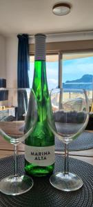 una botella verde de vino y dos copas en una mesa en Esmeralda Suites Sunrise, en Calpe