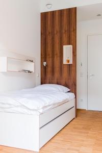 ein weißes Bett in einem Zimmer mit einer Holzwand in der Unterkunft Seminarhaus S1516 in Berlin