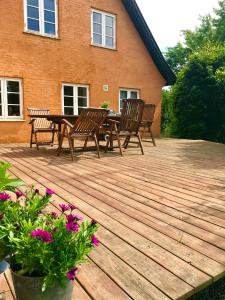 a wooden deck with chairs and a table and flowers at Summer House Svaneke in Svaneke
