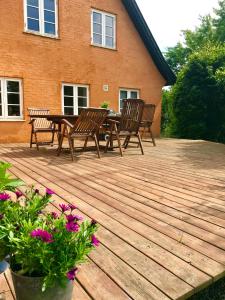 a wooden deck with chairs and a table and flowers at Summer House In Rural Surroundings On Bornholm in Svaneke