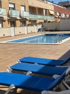 una piscina en la azotea de un edificio con sillas azules en Casa en la playa con piscina en Cubelles