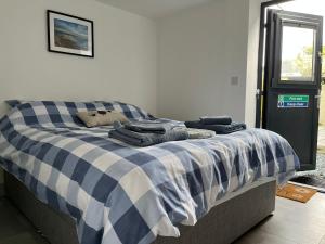 Una cama con una manta azul y blanca a cuadros. en Stonecroft Cwtch, en Haverfordwest