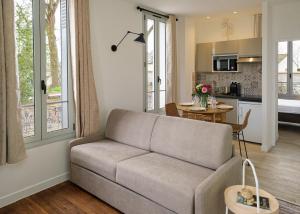 a living room with a couch and a kitchen at Villa Forestière Appart Le Ginkgo in Quincy-Voisins
