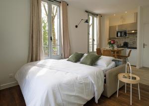 a bedroom with a large white bed and a kitchen at Villa Forestière Appart Le Ginkgo in Quincy-Voisins