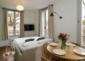 a bedroom with a bed and a table with chairs at Villa Forestière Appart Le Ginkgo in Quincy-Voisins