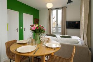 a dining room with a table and a couch at Villa Forestière Appart Le Ginkgo in Quincy-Voisins +5 photos