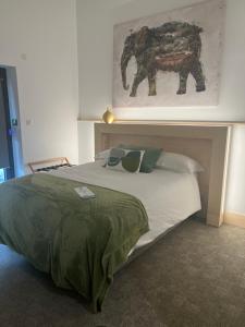 a bedroom with a large bed with a painting on the wall at Le B Complexe Hôtel in Lozanne