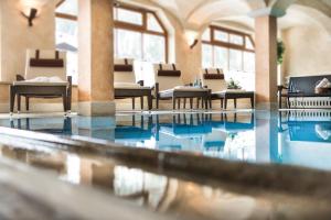 una piscina con mesas y sillas en un edificio en Hotel Alpenhof Superior, en Zauchensee