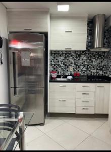 a kitchen with a stainless steel refrigerator and white cabinets at Fortaleza Landscape Beira-mar: espaço inteiro in Fortaleza