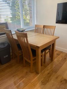 a wooden dining room table with four chairs and a window at Short and Long Night Stay - very close to Gatwick and City Centre - Private Airport Holiday Parking - Early Late Check-ins in Crawley