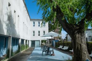 a group of benches and an umbrella next to a building at O2 Hotel Villa Gesell in Villa Gesell
