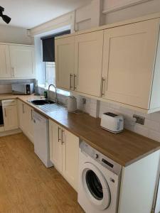 a kitchen with white cabinets and a sink and a dishwasher at Contractor Stays by Furnished Accommodation Manchester - Park Your Van on the Driveway with CCTV in Manchester