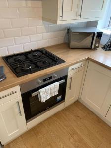 a kitchen with a stove and a microwave at Contractor Stays by Furnished Accommodation Manchester - Park Your Van on the Driveway with CCTV in Manchester