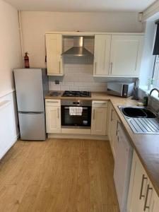 cocina con armarios blancos y nevera blanca en Contractor Stays by Furnished Accommodation Manchester - Park Your Van on the Driveway with CCTV en Mánchester