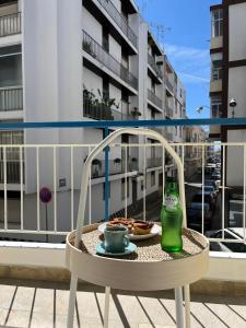 einen Stuhl mit einem Getränk und einem Teller Essen auf dem Balkon in der Unterkunft Flat in Olhão city center in Olhão