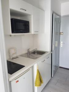 a white kitchen with a sink and a microwave at Studio La Grande Motte, au plus près des plages in La Grande Motte